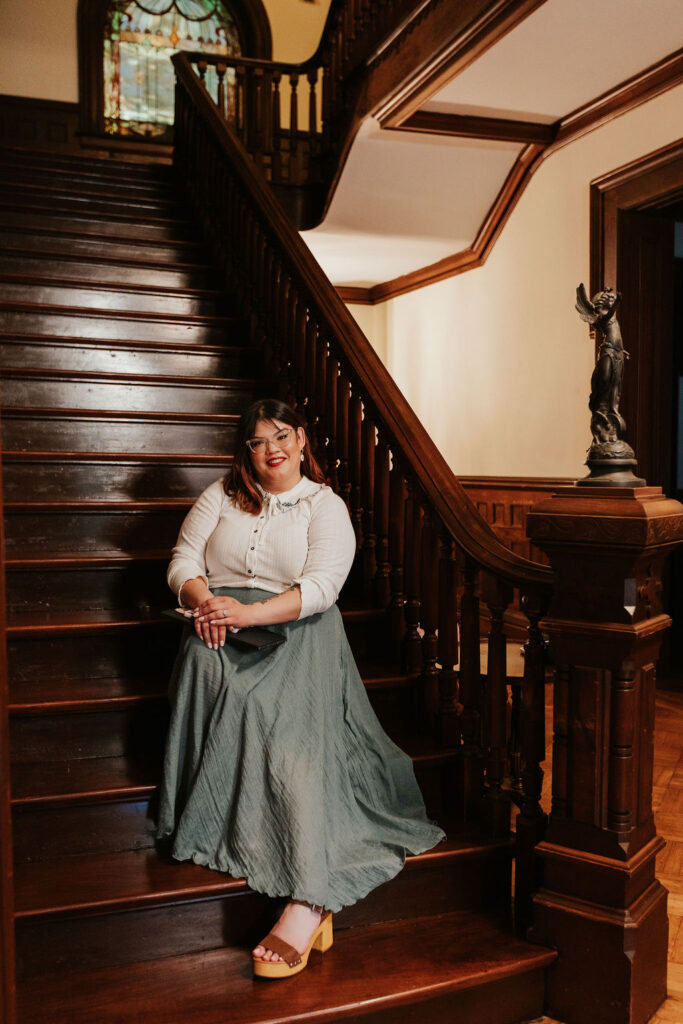 Krystal, founder of Howie Mae, seated on a vintage staircase